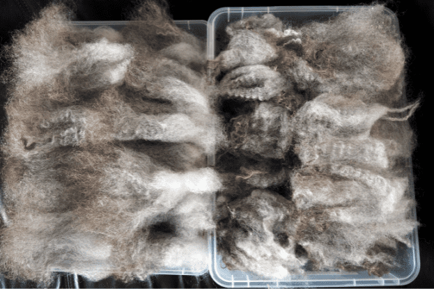 Stapel grauer Wolle in zwei Kisten nebeneinander, geflickt und ungeflickt