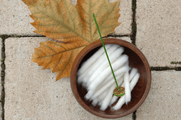 weiße Baumwollpunis in einer Holzschale mit Tahkli auf Terrassensteinen mit Ahornblatt als Dekoration.
