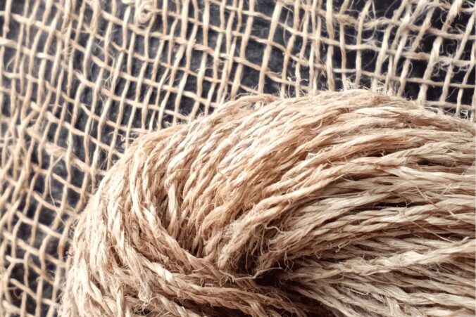 Nahaufnahme eines Stranges Langflachsgarn S/Z vor einer Webprobe , schwarzer Hintergrund.