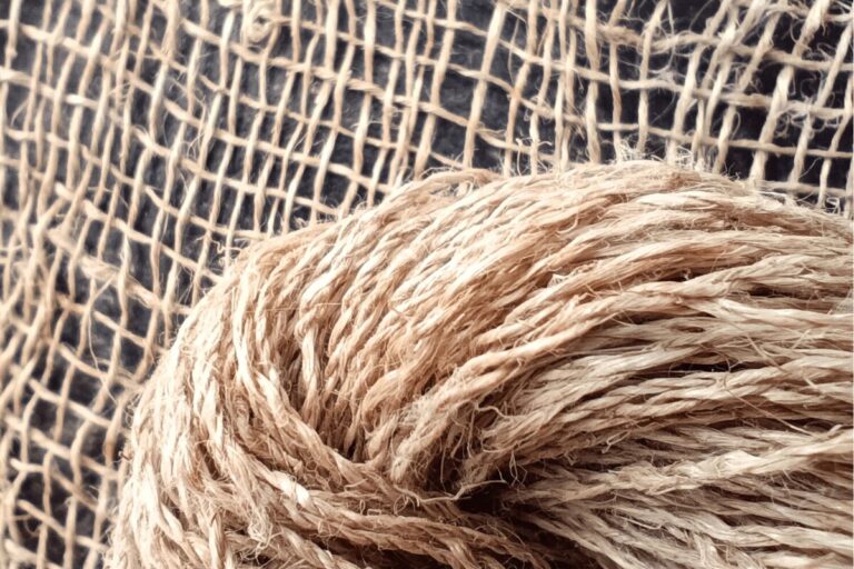 Nahaufnahme eines Stranges Langflachsgarn S/Z vor einer Webprobe , schwarzer Hintergrund.